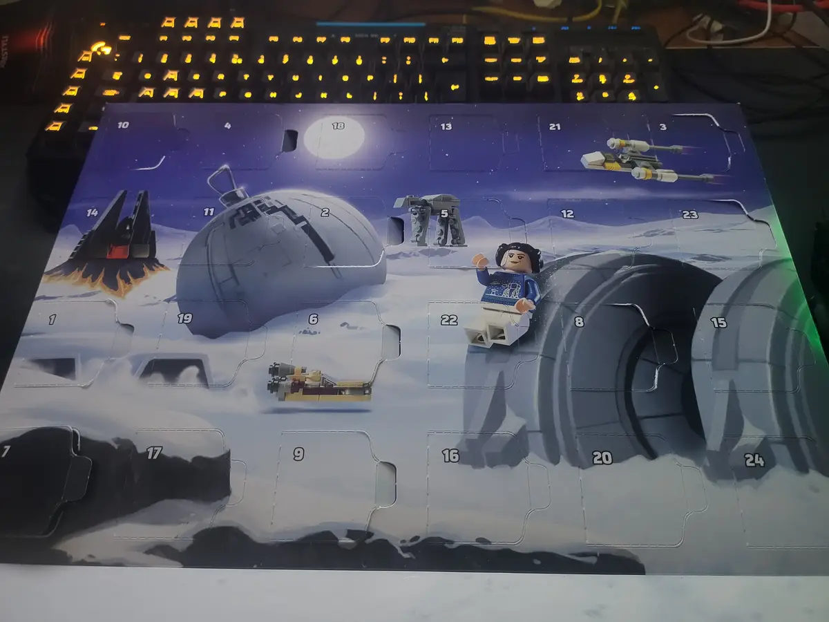 A Lego Star Wars Advent Calendar is shown with several numbered flaps open, revealing Star Wars-themed Lego pieces like a…