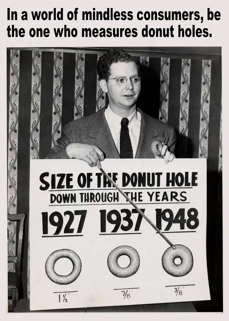 A black-and-white photo shows a man in a suit and glasses holding a sign titled 'SIZE OF THE DONUT HOLE DOWN THROUGH THE…