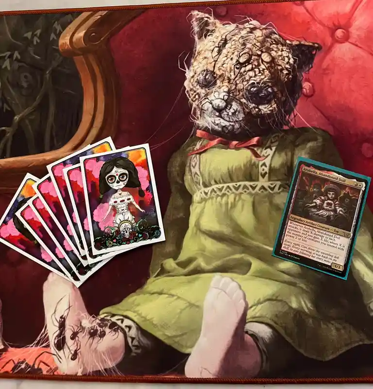 A creepy, spider-infested teddy bear doll in a green dress sits on a red couch, with a Magic: The Gathering card for…