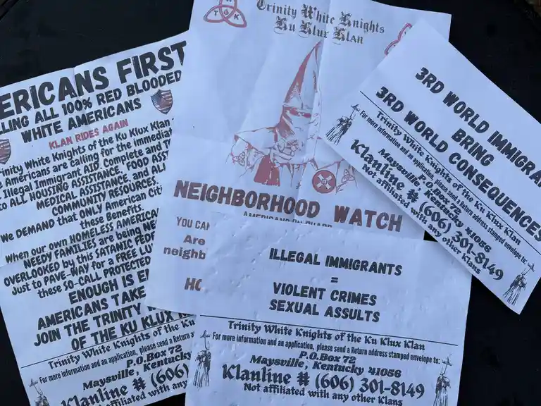 Several flyers from the 'Trinity White Knights of the Ku Klux Klan' are displayed, featuring racist slogans like 'AMERICANS…