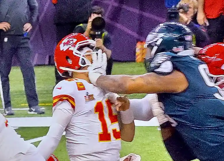 A close-up shot from an american football game shows a kansas city chiefs player in a white jersey with red number 15 being…