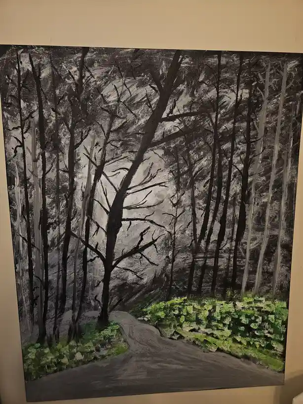 A black-and-white painting of a forest with bare trees and a winding path, where the only color is bright green foliage on…