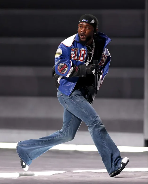 a man in a blue and white jacket with 'GIANTS' and '10' on the front, wearing a black cap, jeans, and gloves, is running on…