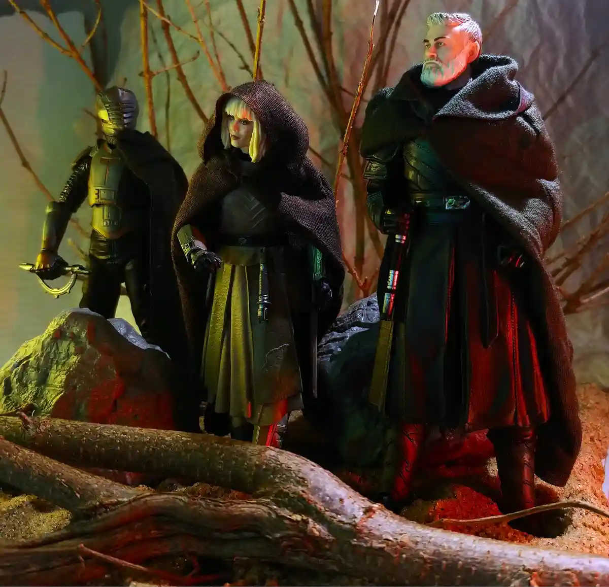 Three Star Wars action figures — a helmeted warrior, a hooded woman with blonde hair, and a bearded man in a cloak — stand…