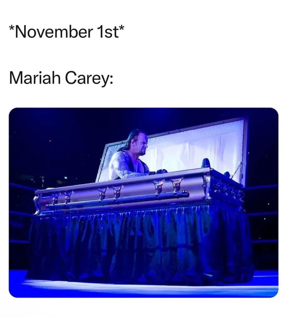 A man with long hair and tattoos sits inside an ornate, open casket on a wrestling ring, illuminated by blue stage lighting…