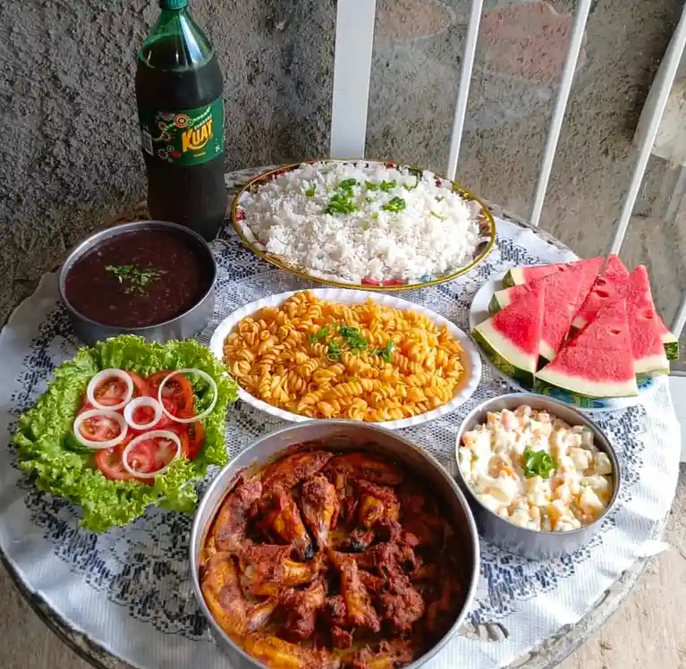 A table is laden with a colorful spread of food including a large bowl of stewed meat, a plate of white rice with green…