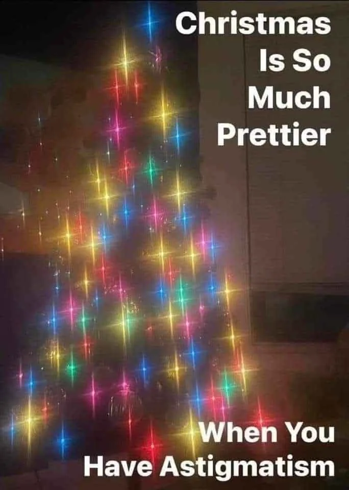 A blurry, out-of-focus image of a Christmas tree covered in colorful, starburst-style lights, with white text overlaid in…