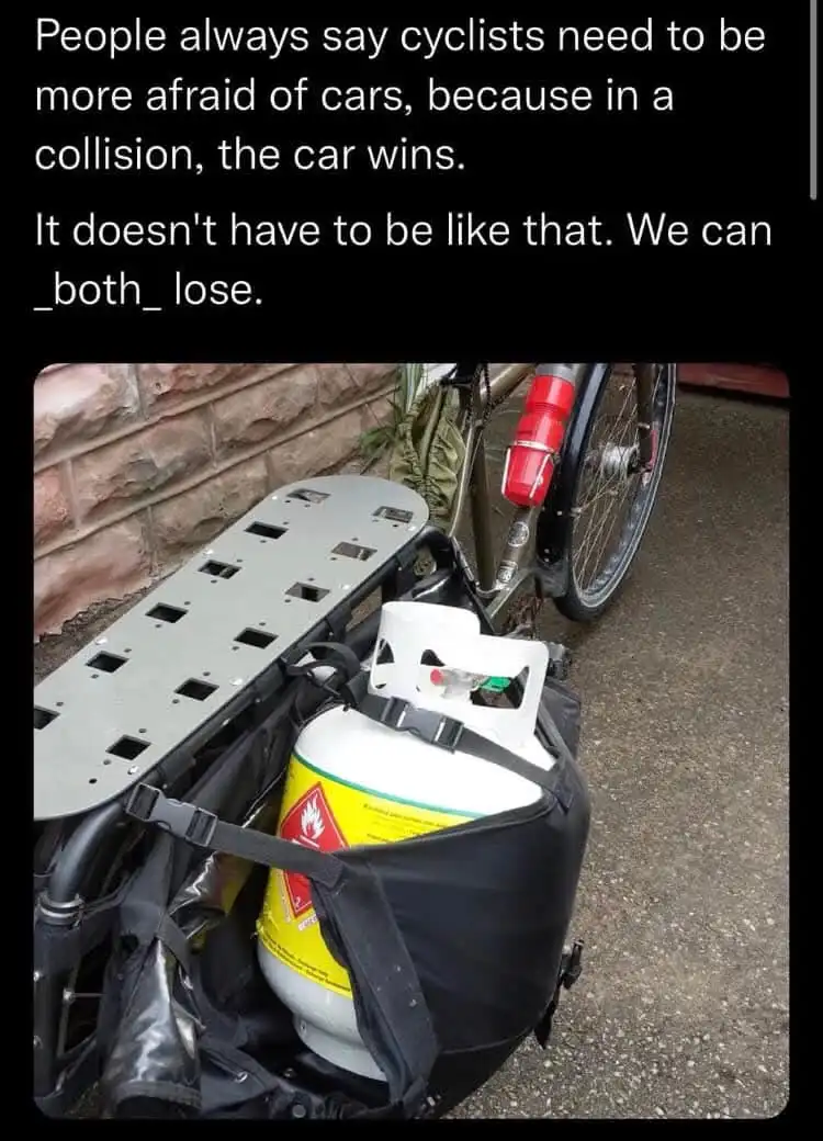 A bicycle with a large metal cargo rack attached to the back, carrying a white propane tank in a black bag. The tank has a…