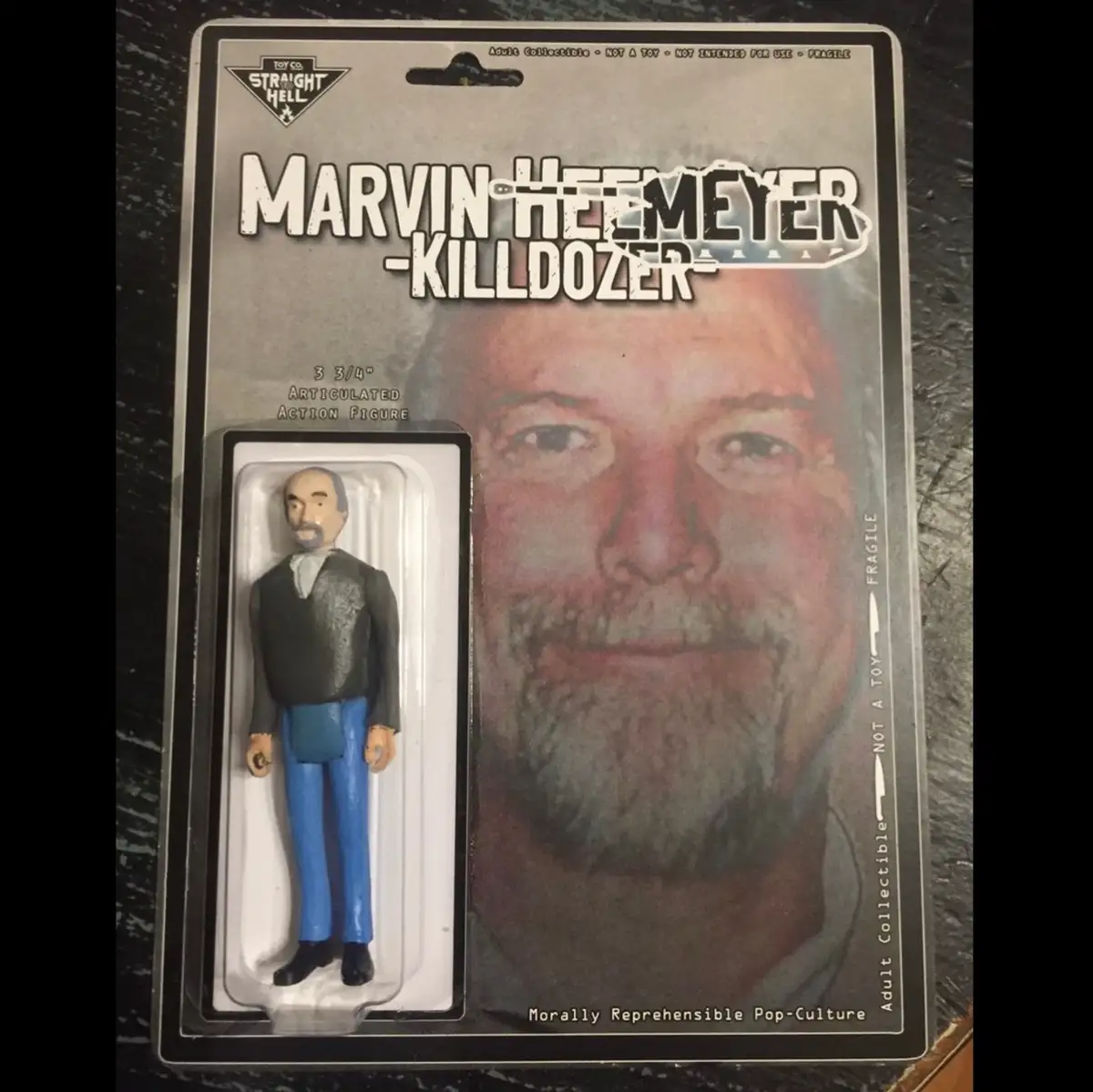 A collectible action figure of Marvin Heemeyer, labeled 'Killdozer', is shown in its packaging. The packaging features a…