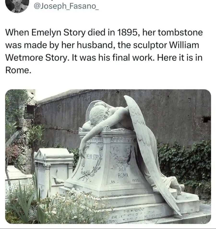 A black-and-white photo shows a large, ornate stone tombstone in a cemetery. An angelic figure with large wings is carved…
