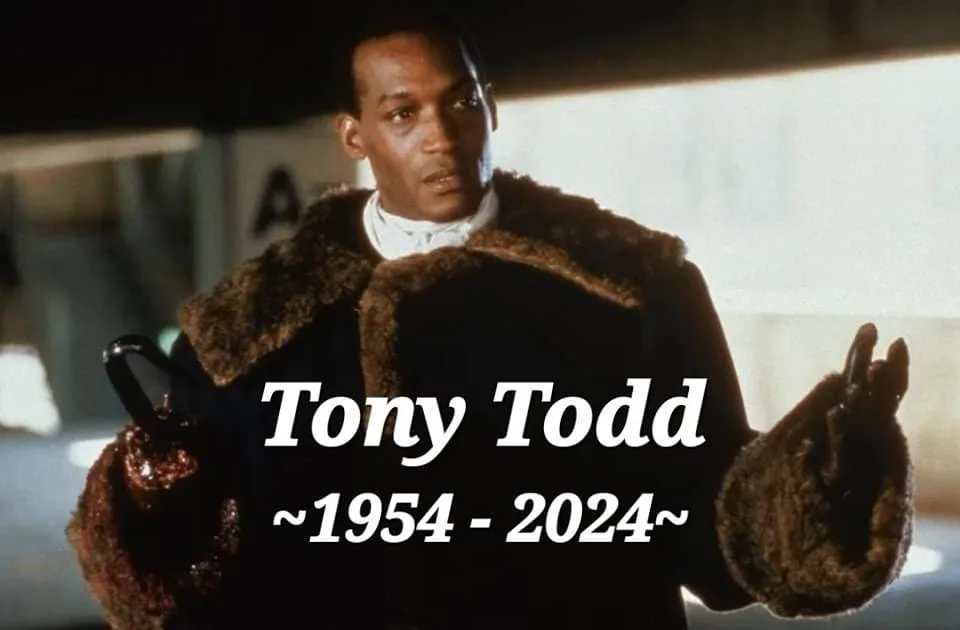 A still image of actor Tony Todd wearing a dark coat with a brown fur collar and holding a cane, looking serious. White text…