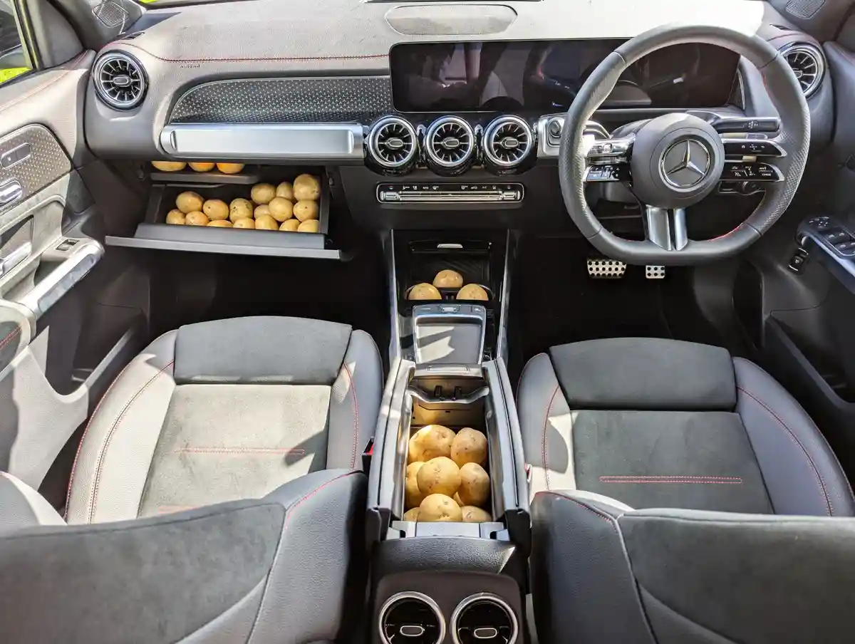 The interior of a luxury Mercedes-Benz car, featuring a modern dashboard, steering wheel, and seats, is filled with potatoes…