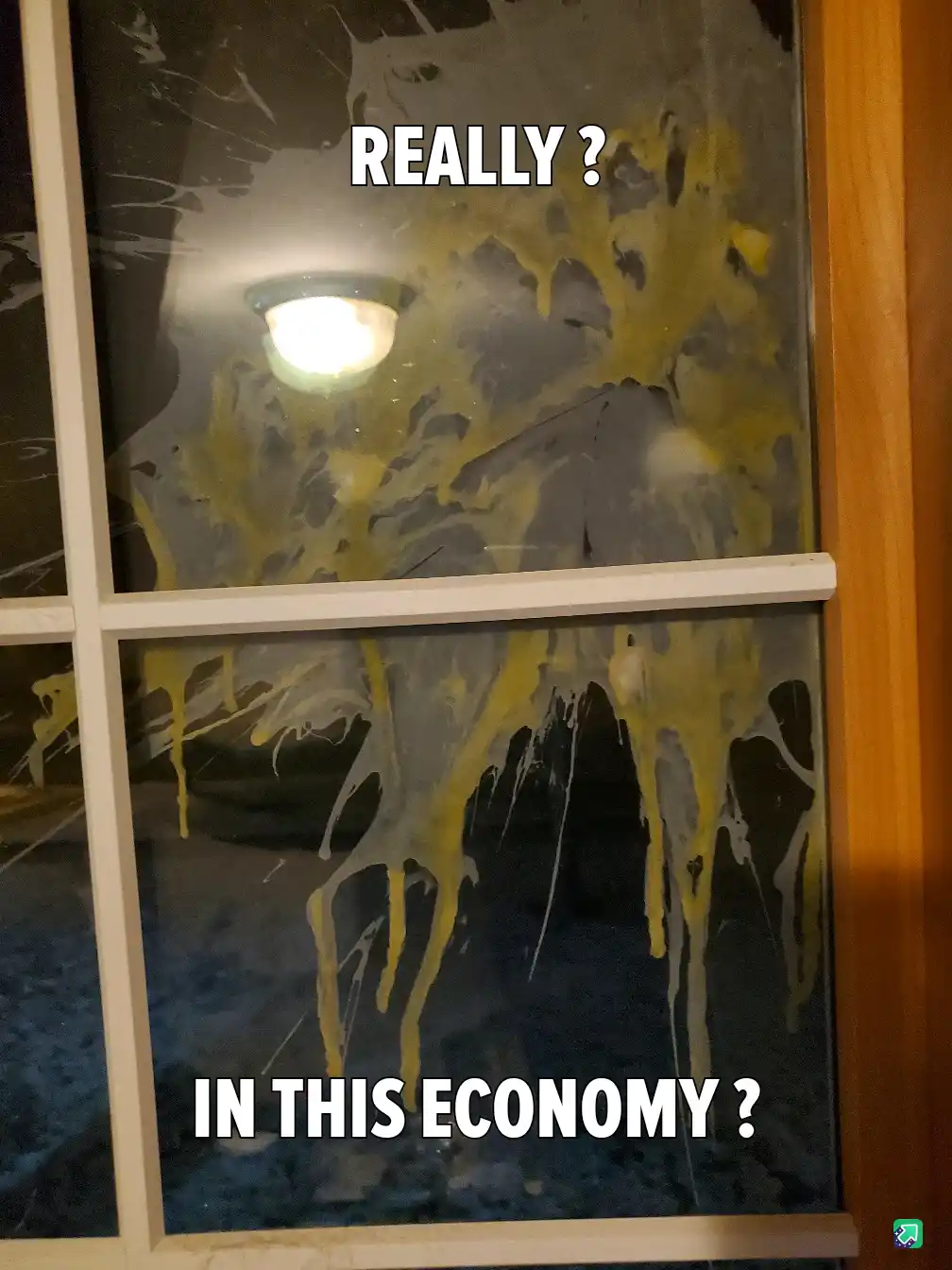 A window pane is heavily smeared with yellow and white cleaning solution, obscuring the view of a bright ceiling light and…