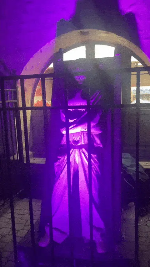 A six-panel image shows a person in a long, flowing purple dress standing behind a black metal fence in a dimly lit…