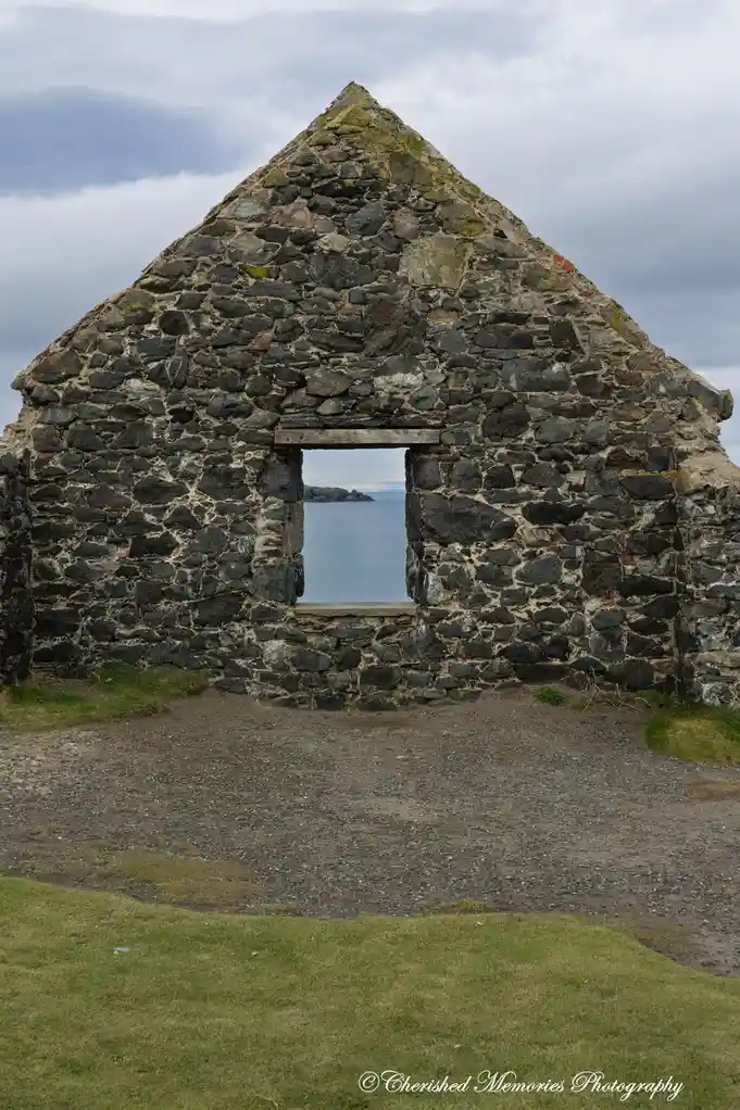A stone ruin with a rectangular window frame looks out onto a calm sea under a cloudy sky. The overlaid text reads 'i'm not…