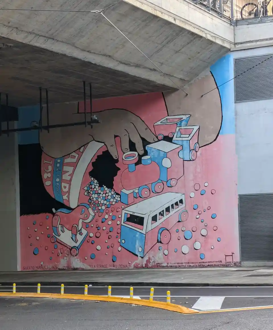 A mural under a concrete overpass depicts a giant hand holding a broken toy train and bus, spilling colorful dots, with text…