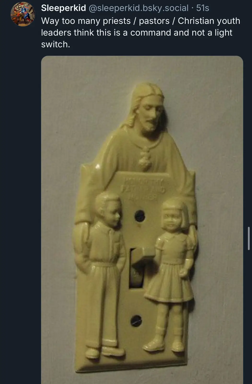A beige light switch plate features a raised relief of Jesus Christ holding a book, flanked by a boy and a girl, with the…