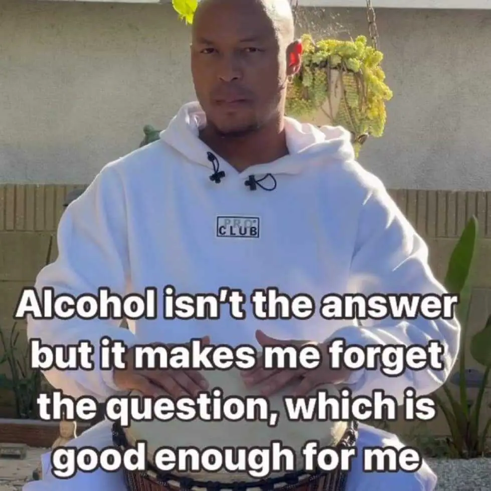 A man in a white hoodie sits outdoors with a serious expression, hands clasped. Overlaid text reads: 'Alcohol isn't the…