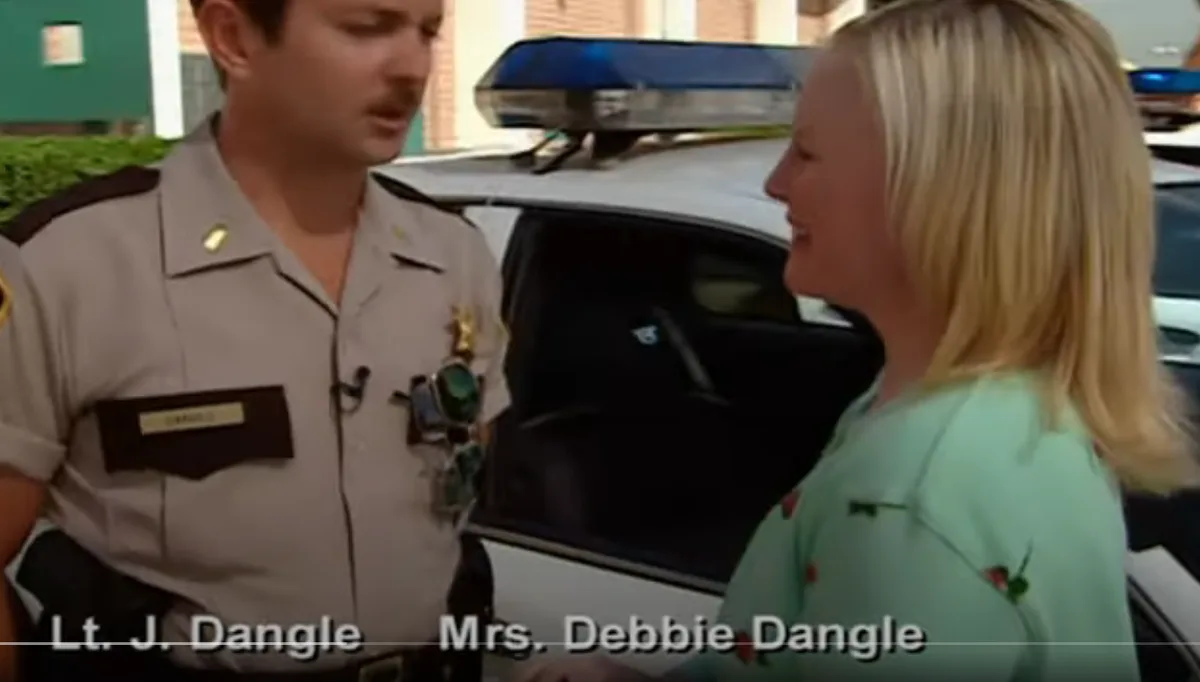A man in a police uniform labeled 'Lt. J. Dangle' stands beside a woman in a light green floral shirt labeled 'Mrs. Debbie…