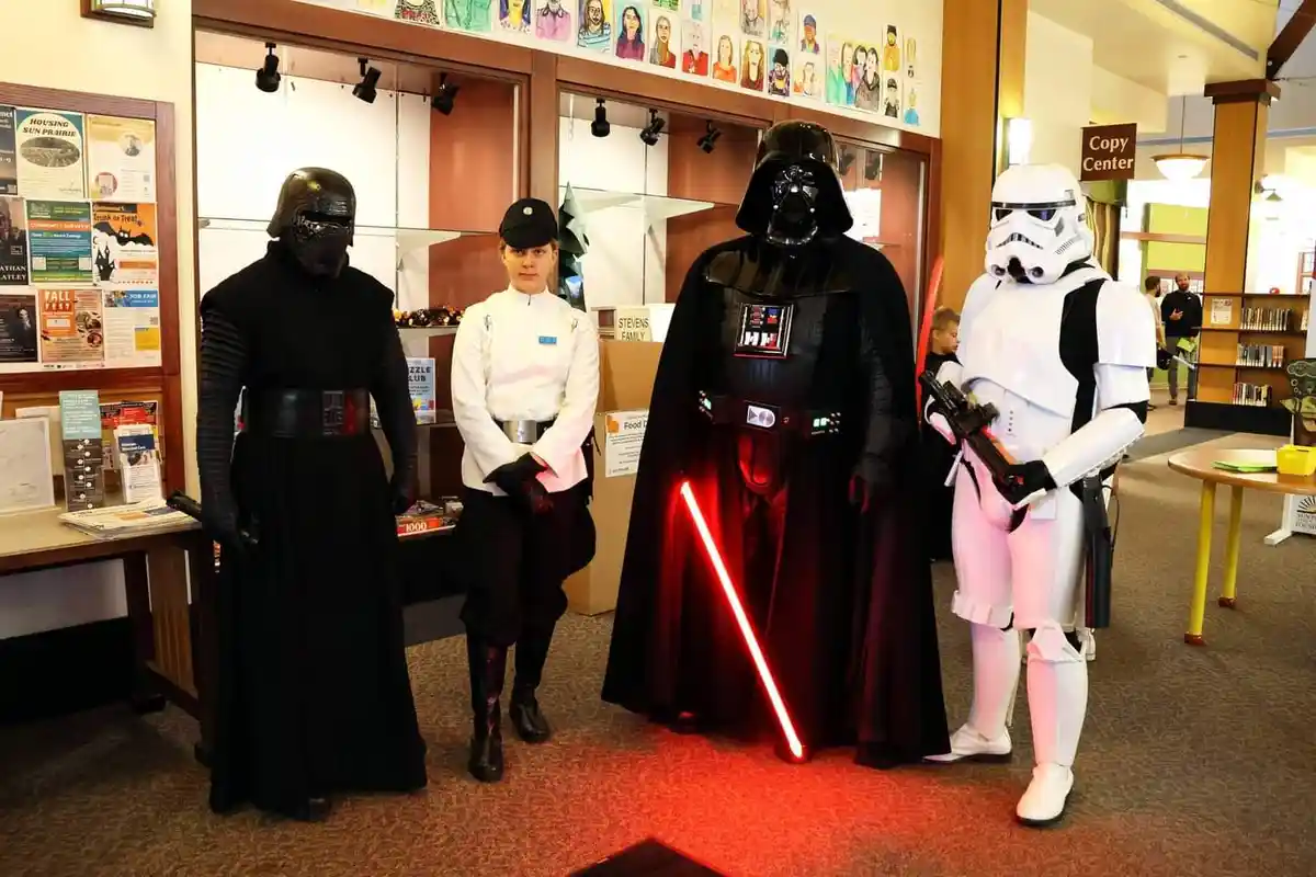 Four people dressed as Star Wars characters — Kylo Ren, a Stormtrooper, Darth Vader holding a red lightsaber, and a person…