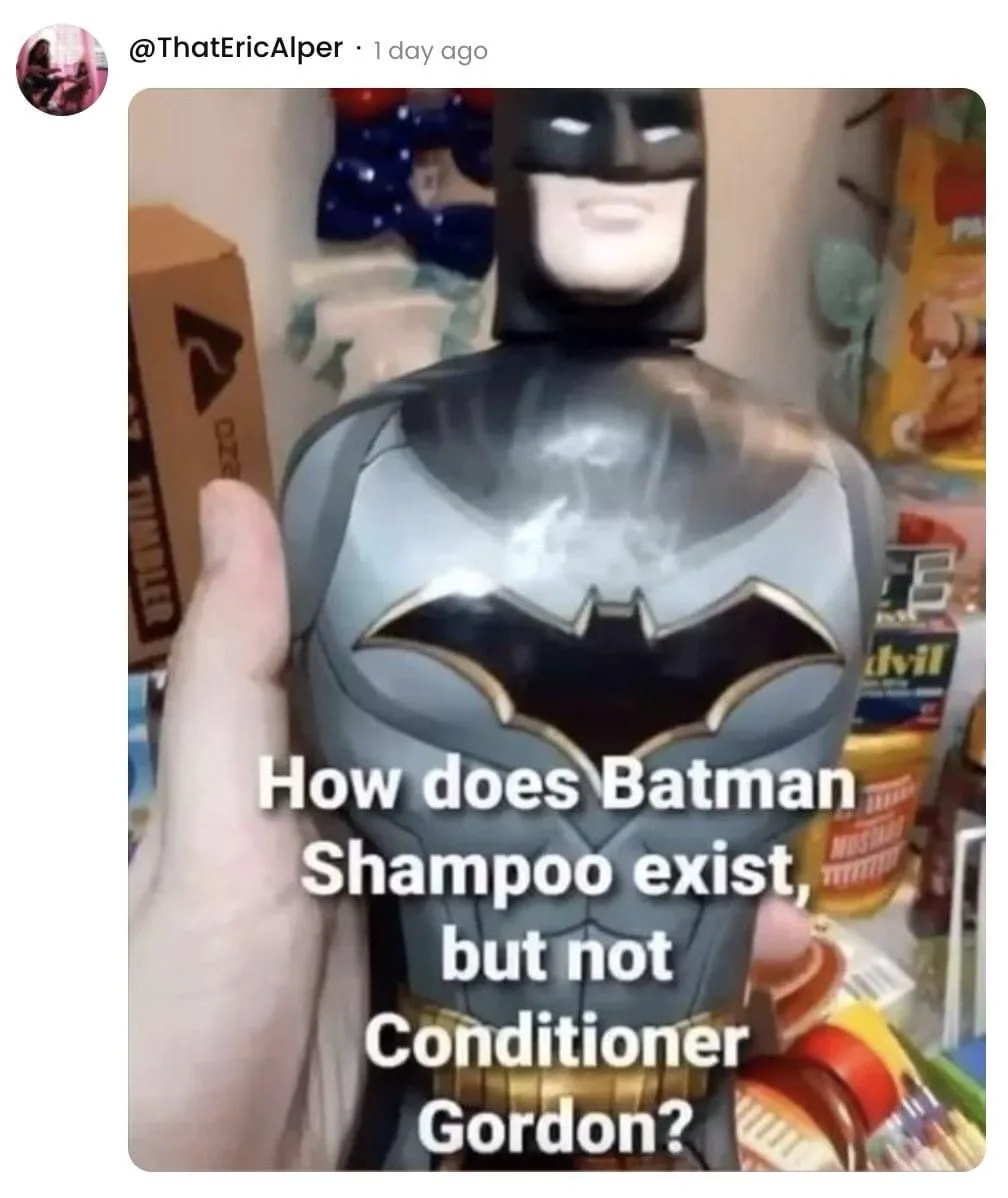 A hand holds a Batman-themed shampoo bottle shaped like the superhero's torso, featuring his iconic black and grey suit with…