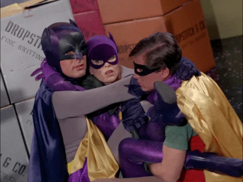six identical frames show Batman and Batgirl hugging Robin, who is looking away with a slightly annoyed or embarrassed…