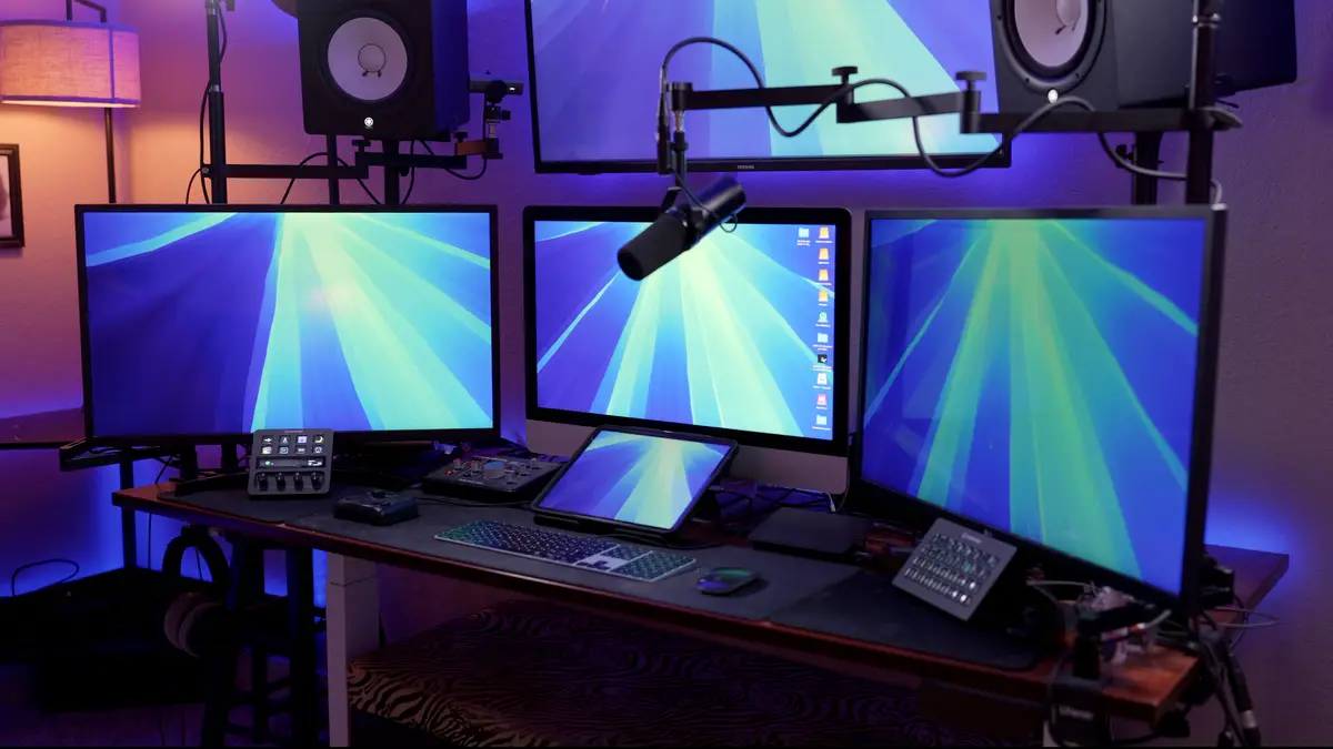 A professional-looking computer setup with multiple monitors displaying a blue and green radial gradient wallpaper, a large…