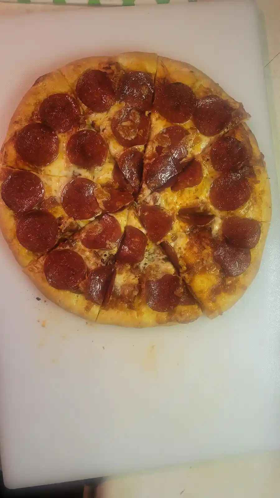 A top-down photo of a pepperoni pizza on a white cutting board, with one slice slightly pulled away. The overlaid text reads…