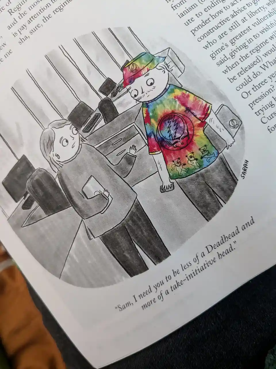 A cartoon depicts a person in a tie-dye Deadhead t-shirt and hat standing in an office, while another person in a grey shirt…