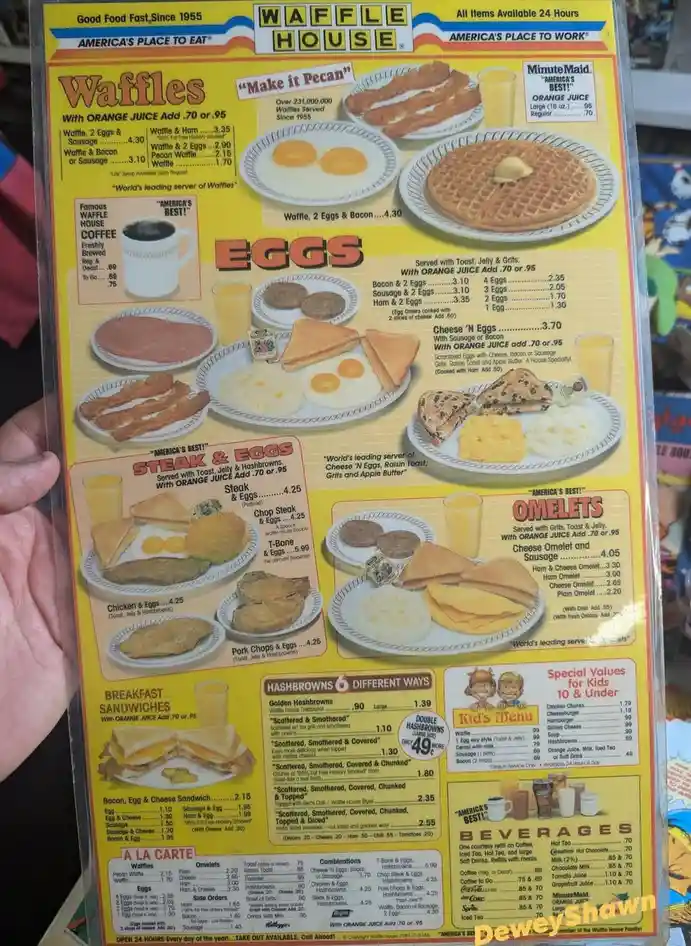 A person holds up a Waffle House breakfast menu featuring sections for waffles, eggs, steak & eggs, omelets, sandwiches…