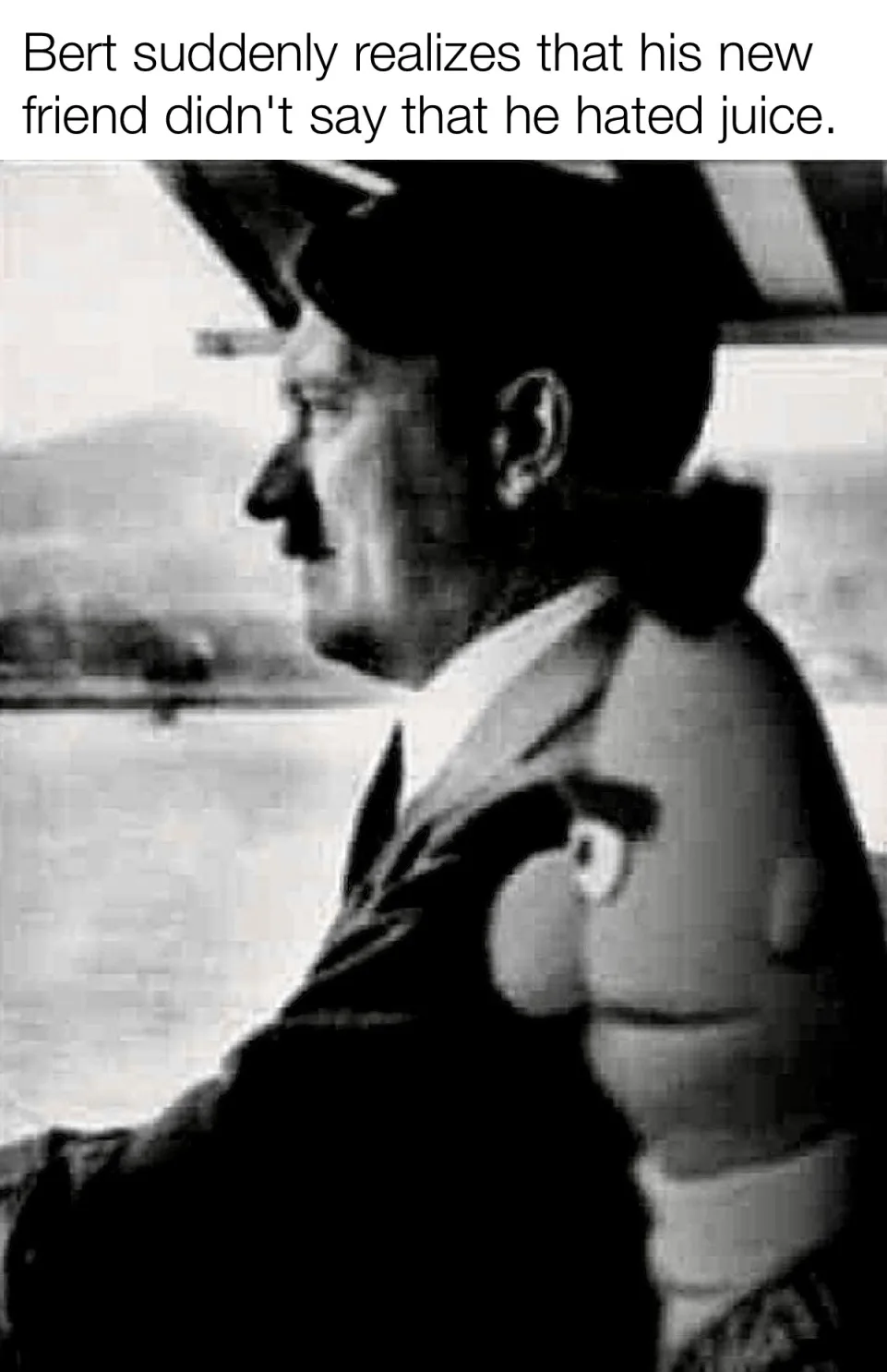 A black-and-white photo shows a man in profile wearing a hat and suit, looking off to the side with a serious expression…