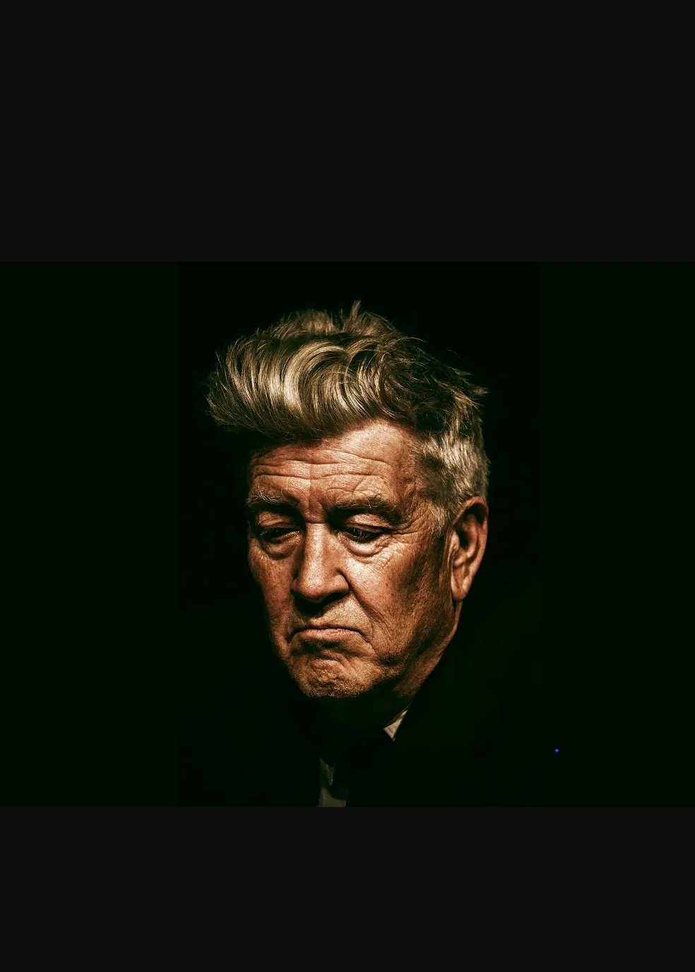A close-up portrait of an older man with graying hair and a somber, disapproving expression, set against a dark background…