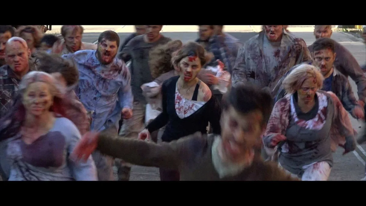 A chaotic scene from a zombie movie shows a horde of bloodied, decaying zombies lunging forward on a street. The overlaid…