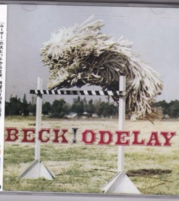 An album cover for Beck's 'Odelay' shows a large, fluffy, light-colored pom-pom-like object balanced precariously atop a…