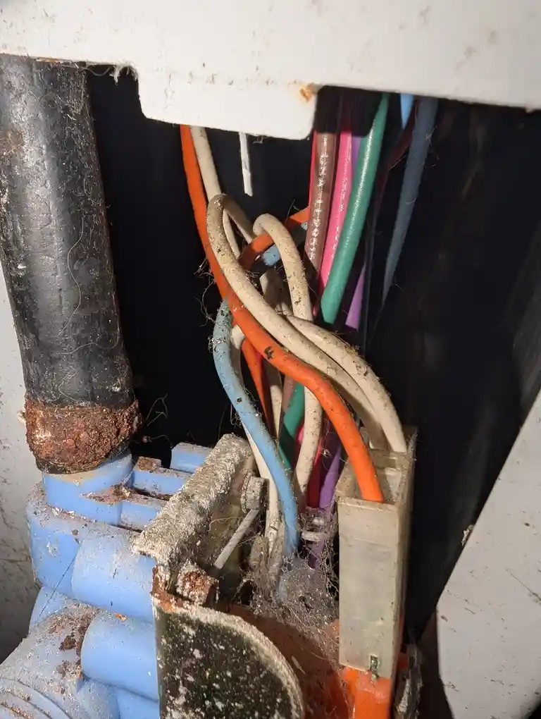 A close-up photo shows a messy, dusty electrical junction box with tangled, multicolored wires (orange, white, blue, pink…
