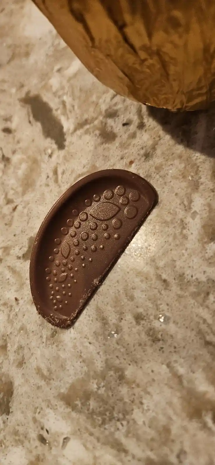 A close-up photo shows a brown chocolate bar molded into the shape of a remote control, complete with raised button…