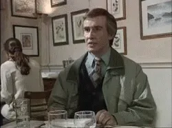 A six-panel sequence shows a man in a green jacket and tie sitting at a restaurant table, progressively reacting with…