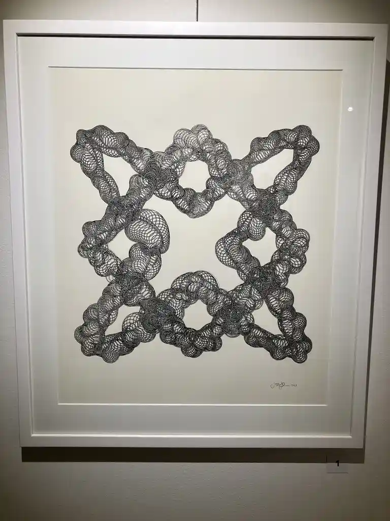 A framed black-and-white abstract drawing featuring intricate, swirling, rope-like patterns forming a symmetrical, star-like…