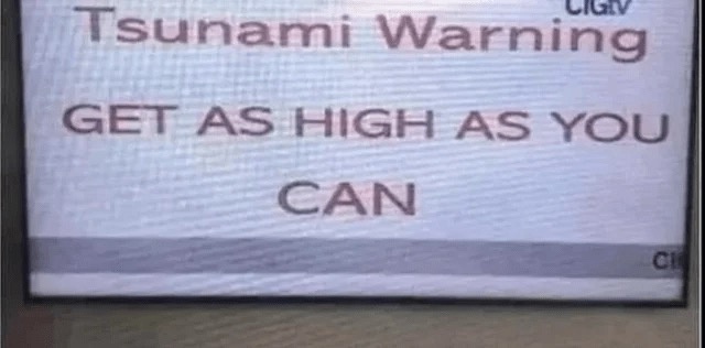A close-up of a television screen displaying a tsunami warning message in bold, uppercase letters. The text reads 'Tsunami…