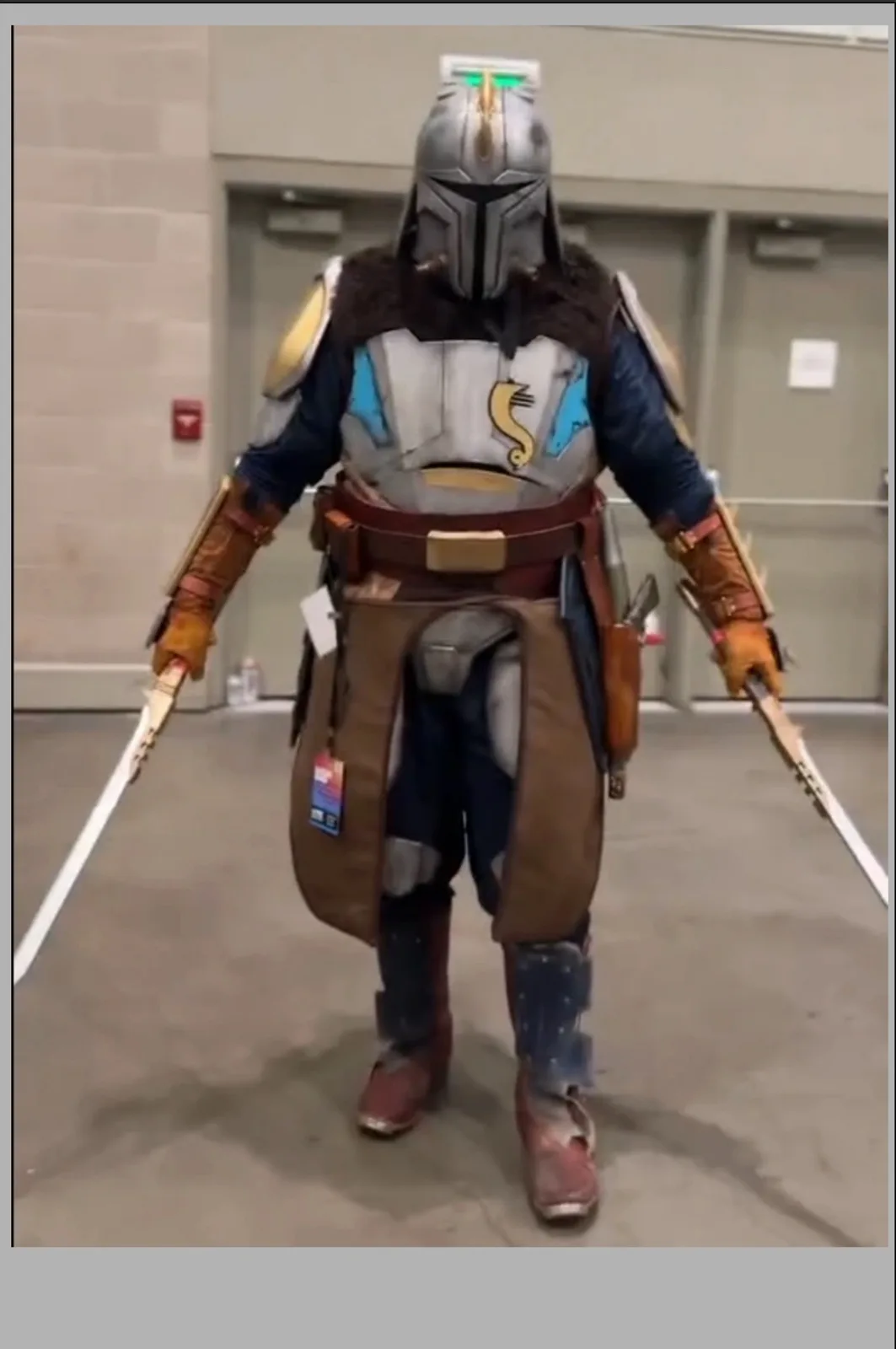 A person in a Mandalorian cosplayer costume, featuring a helmet with green glowing eyes, a chest plate with a yellow…