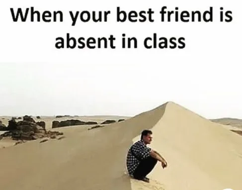 A man in a checkered shirt sits alone on the edge of a large sand dune in a barren desert landscape, looking off into the…