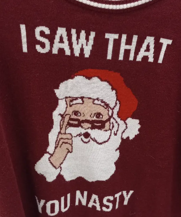 A close-up of a maroon knit sweater featuring a pixelated graphic of Santa Claus with a red hat and white beard, holding up…