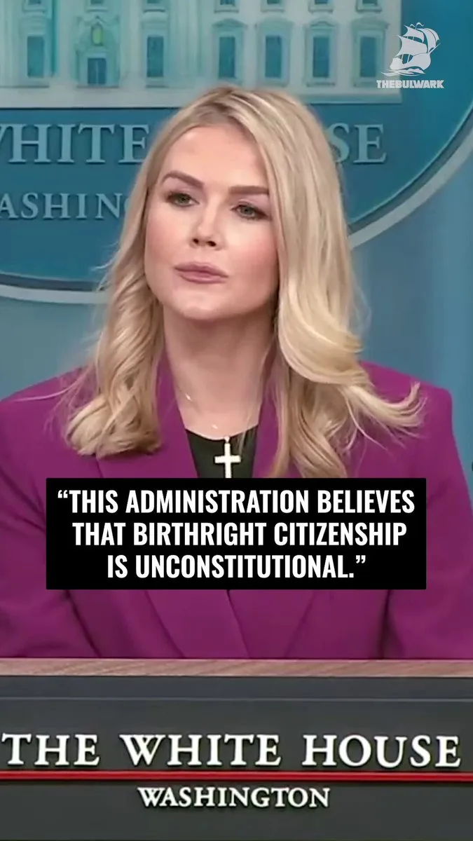 A woman with blonde hair wearing a purple blazer and a cross necklace stands at a podium in front of a White House backdrop…