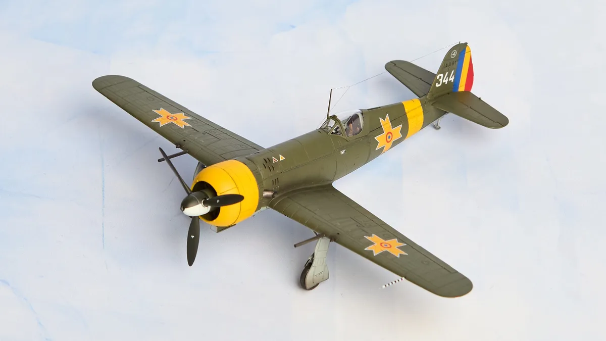 A detailed scale model of a Romanian military aircraft, painted in olive green with yellow accents and national insignia…