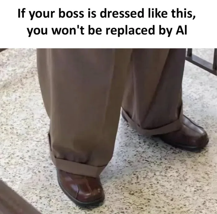 The image shows the lower half of a person wearing brown trousers with cuffs rolled down over brown leather dress shoes…