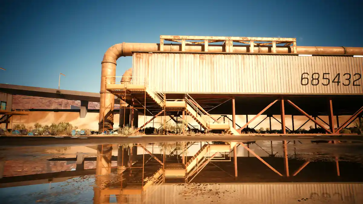 A rusty industrial building with a large number '685432' painted on its side, reflected in a puddle of water in the…