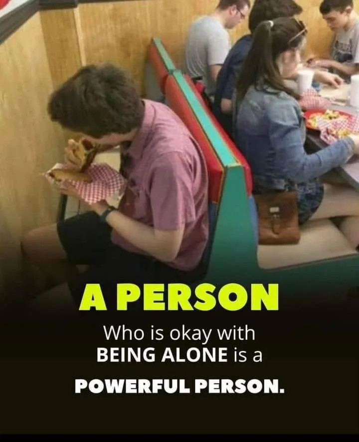 A young man in a pink shirt sits alone on a diner booth, eating a sandwich while others sit at adjacent tables. The text…