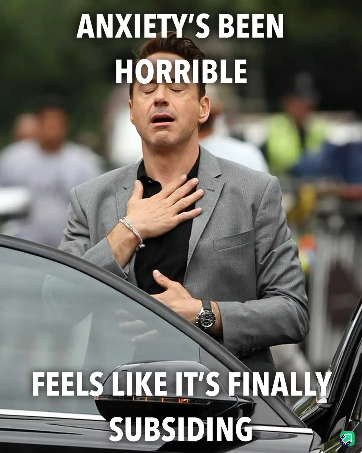 A man in a grey suit stands by a car, hands on his chest, eyes closed, looking exhausted or relieved. White bold text…