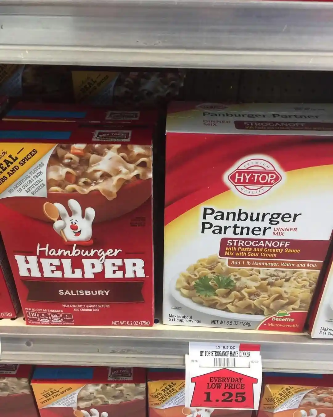 A grocery store shelf displays two red boxes of dinner mixes side by side: 'Hamburger Helper Salisbury' on the left and…