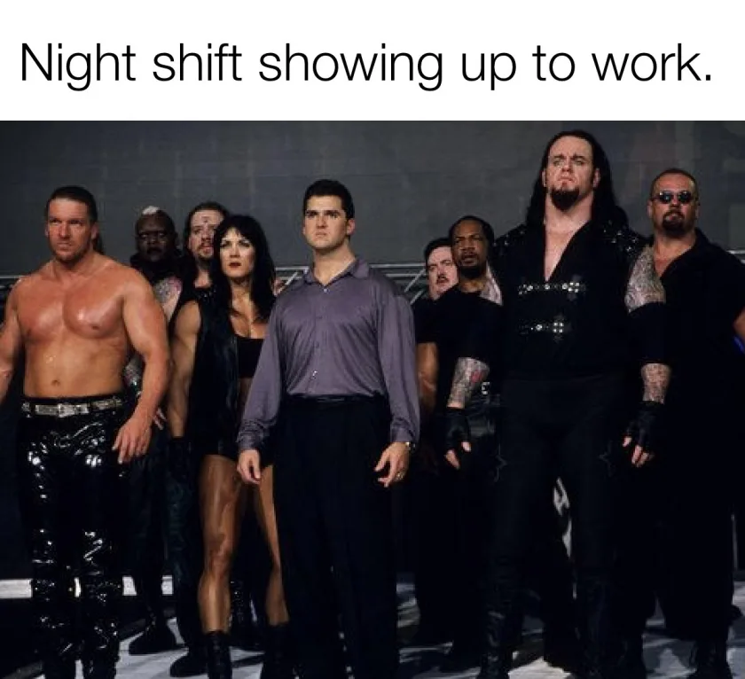 A group of WWE wrestlers, including The Undertaker and Kane, stand menacingly behind a single man in a plain purple shirt…